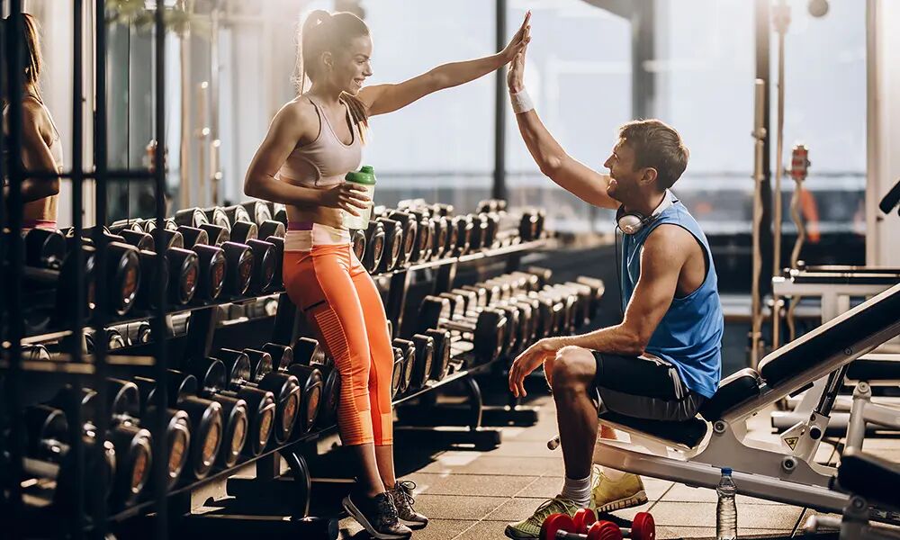 Mann und Frau in einem Fitnessstudio klatschen sich ab